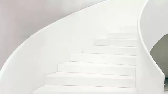 Un escalier en colima&ccedil;on blanc, moderne et minimaliste, aux courbes douces, s'&eacute;l&egrave;ve le long d'un mur clair, &eacute;voquant une impression d'&eacute;l&eacute;gance et de simplicit&eacute;.