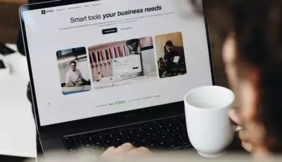  Une personne utilisant un ordinateur portable sur lequel s'affiche le site web d'une entreprise, avec le texte &laquo; Les outils intelligents dont votre entreprise a besoin &raquo;, entour&eacute; d'images de professionnels. La sc&egrave;ne d&eacute;gage une impression de concentration et de productivit&eacute;.